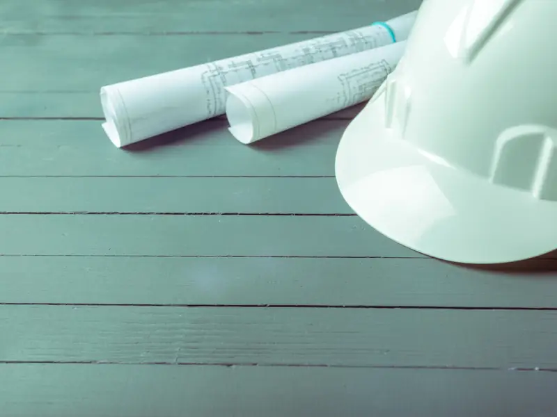 Casco de seguridad y planos enrollados sobre una mesa de trabajo