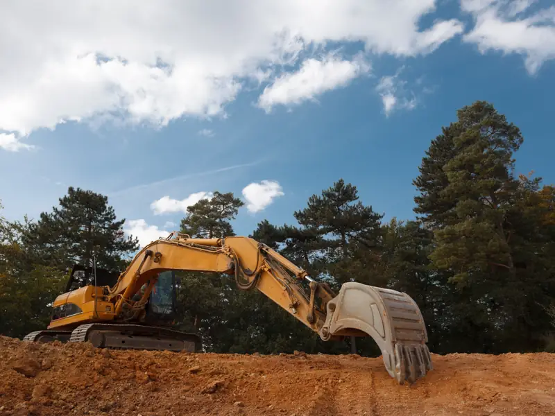 Excavadora trabajando sobre un terraplén de tierra bajo cielo despejado