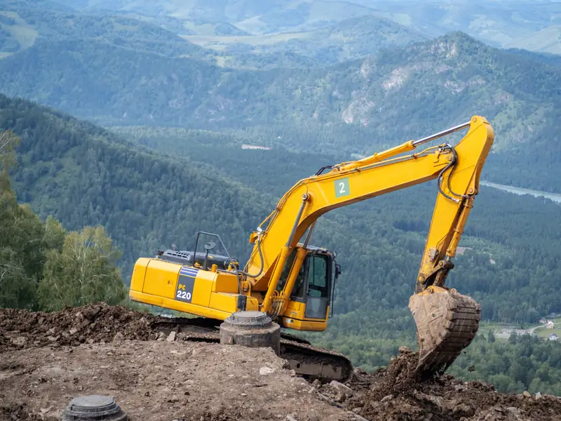 Excavadora nivelando una ladera con un valle al fondo