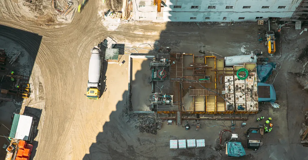 Vista aérea de una cimentación en obra con revolvedora de concreto y cuadrillas trabajando