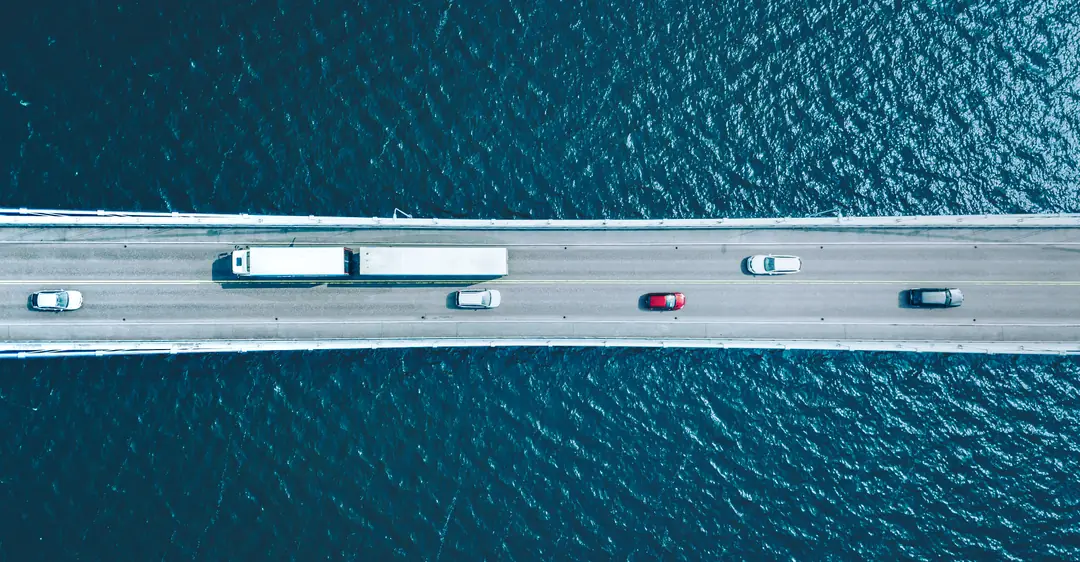 Vista aérea de un tractocamión cruzando un puente sobre el mar