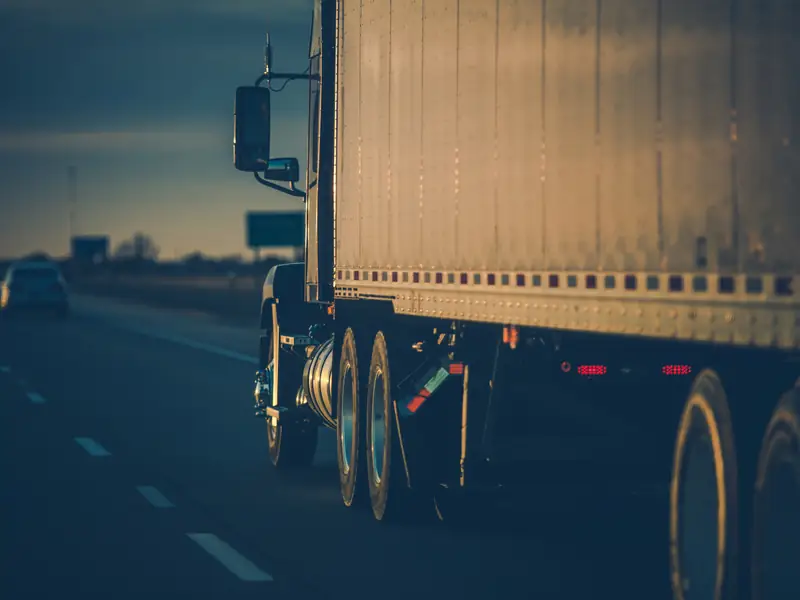 Tractocamión con caja seca circulando por autopista al atardecer